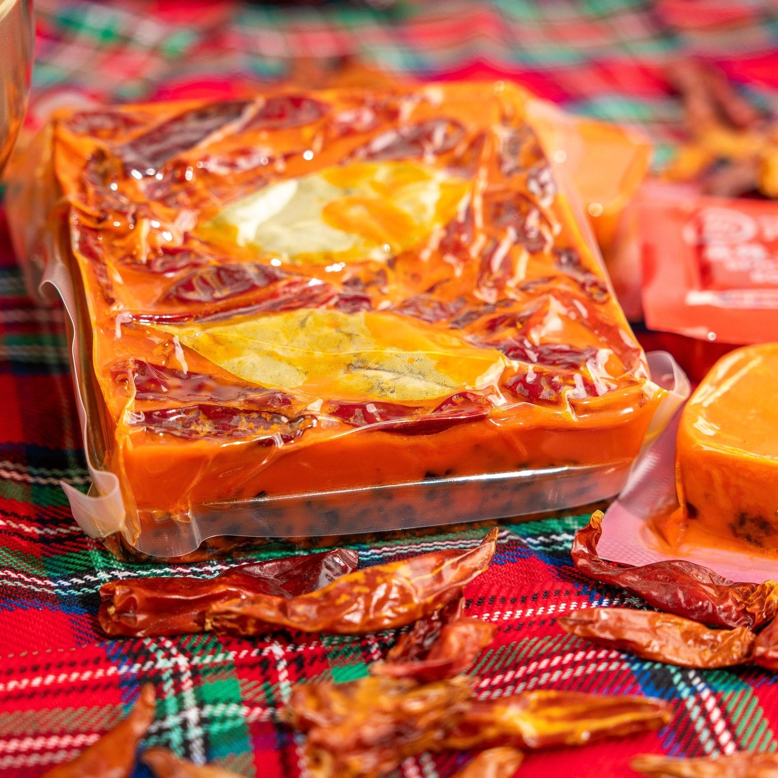 Close-up of HAIDILAO mala hot pot soup base block showing chili peppers, bay leaves, and spices sealed in packaging