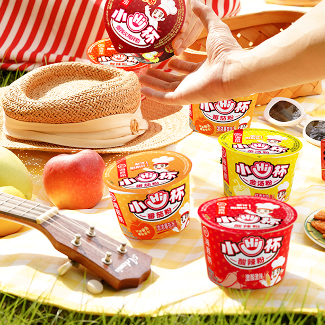HAIDILAO Mini Cup noodles at an outdoor picnic with hat, sunglasses, apple, and ukulele