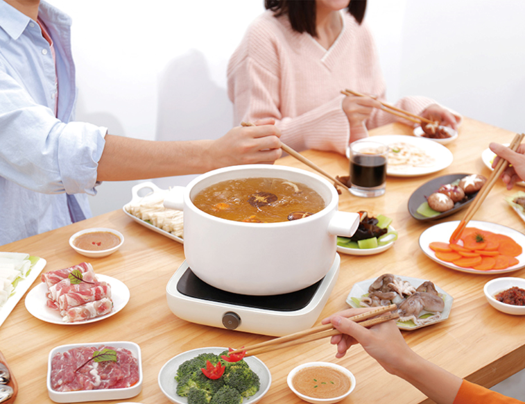 Friends enjoying HAIDILAO Mushroom Hot Pot together at a table with sliced meat and vegetables